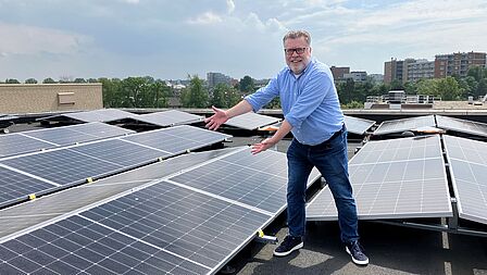 Wethouder Piet Burgering laat de nieuwe zonnepanelen op het dak van het gemeentehuis zien.
